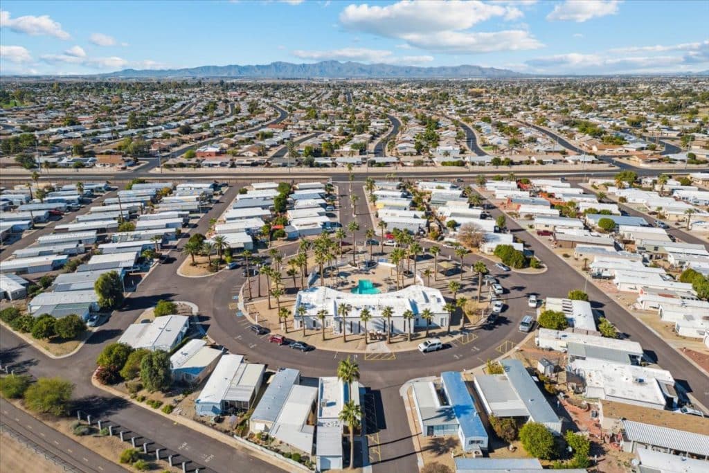Aerial view of a large residential community with white homes, circular central plaza, and mountainous landscape in the distance in peoria az